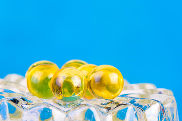 Fish fat round pills on blue background, medicine capsule contains omega 3 vitamin