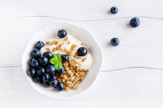 Healthy  breakfast granola with blueberries and yogurt in a bowl on a white table top view