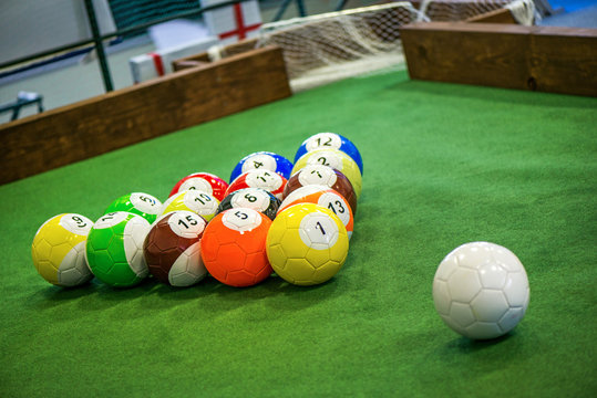 Shot of foot pool balls standing on green table. Foot Pool is the hybrid combination of pool and soccer. Big billiard balls. 