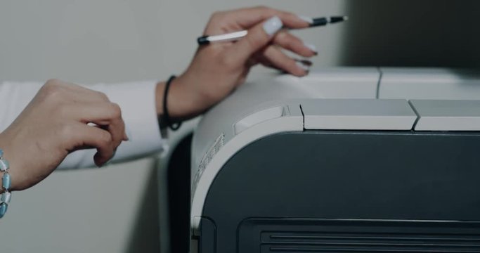 Closeup female hands , printing some papers in the office