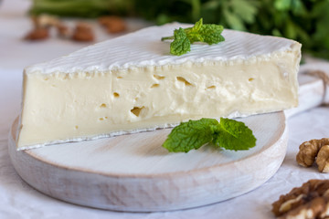 Fresh Brie cheese  on a wooden board with nuts