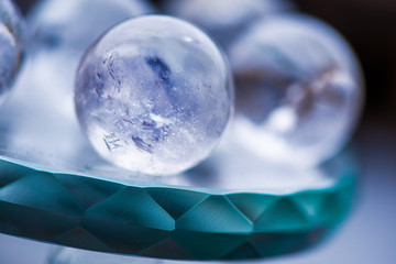 Macro shot of transparent crystal balls with colorful ornaments and sun reflections in it, on turquoise glass pad. Fortune telling. Love, money, luck, success.