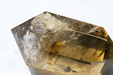 Macro shot of citrine stone on white background. Yellow, clear crystal with a dark, smokey color, smoky quartz with ornaments and rainbows in it. Powerful source of energy and healing.