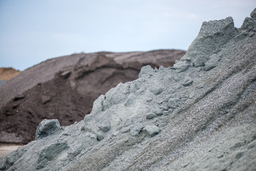 Fototapeta premium Large piles of construction sand and gravel used for asphalt production and building. Limestone quarry, mining rocks and stones