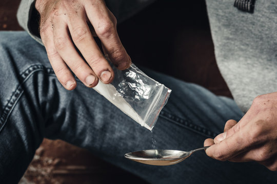 A young man makes heroin in, preparing to take heroin, pours heroin into a spoon. The concept of crime and drug addiction