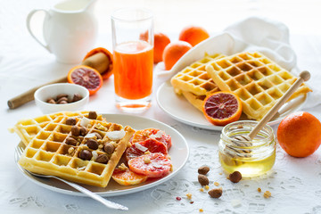 Healthy breakfast. Belgian waffles with nuts and blood oranges on the white table
