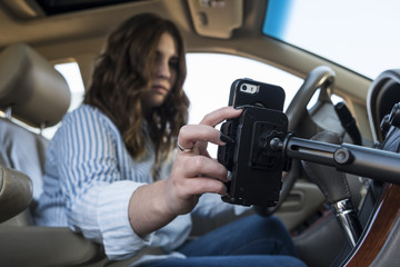 Young woman distracted with cell phone while driving a car