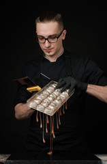 Chocolatier in black uniform in the process of making chocolates