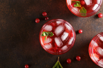Three glasses with refreshment summer cranberry drink on the rusty background.