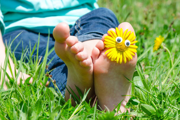 Kinderfüße mit Blumen auf Frühlingswiese