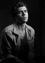 Thinking serious charismatic man in blue jeans looking on dark shadow dramatic light background. Closeup portrait. Black and white