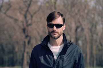 portrait of a bearded man wearing sunglasses in a park.