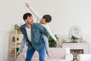 A great father is one whose children look up to him! Flying young boy sitting on his father's back spending his free time with a great pleasure.