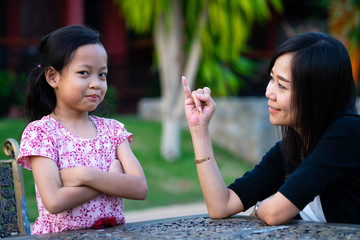 Frowned daughter are little smile and mother apologized for showing her little finger.