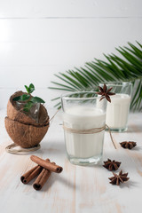 Shell of coconut and coconut milk in glass with cinnamon on wooden table.