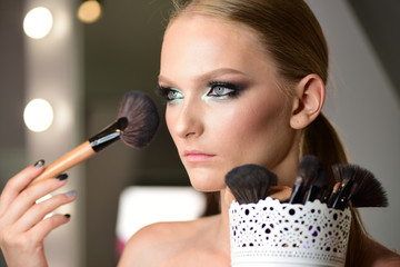 Beautiful woman face powder, and apply blush to cheekbones
