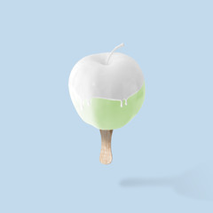 Green apple with ice cream stick on blue background. Food minimal concept.