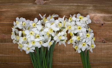 Two bouquets of fresh narcissus on a wooden table. Spring and celebration concept background. 