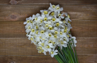 Big bouquet of fresh narcissus on a wooden table. Spring and celebration concept background. 