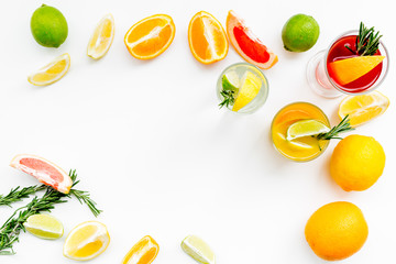 Concept of alcoholic cocktail with fruits. Glass with beverage near oranges, grapefruit, lime and rosemary on white background top view copy space