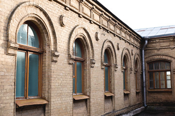 Obraz premium five vintage arched windows in a wall of yellow bricks. Green - the colors of sea wave glass in a maroon dark red wooden frame. The concept of antique vintage architecture in building elements