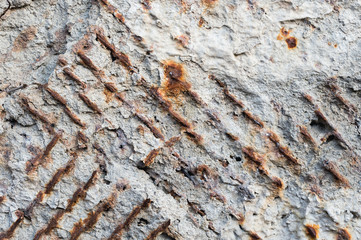 Textured background of an old concrete wall with a rusty outwardly extending reinforced armature....