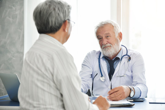 Senior male Doctor is talking with Asian male patient.