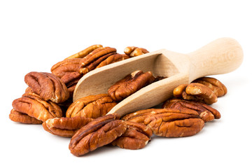 Pile of peeled pecans and wooden spoon on a white, isolated.