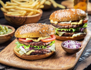 Hamburgers and French fries on the wooden tray.