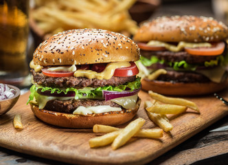 Hamburgers and French fries on the wooden tray.