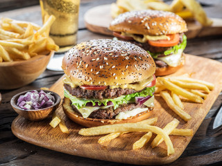 Hamburgers and French fries on the wooden tray.