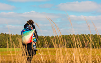 Mom with child in a baby sling while going for a walk
