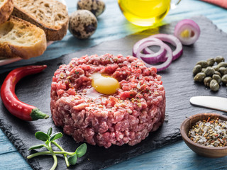 Steak tartare served with raw quail egg yolk, capers and bread. Meat dish.