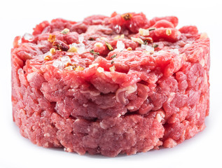 Ground cutlet or raw hamburger with seasonings on white background. Close-up.