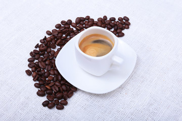 Fresh tasty espresso cup of hot coffee with coffee beans on white background.