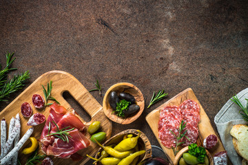 Antipasto - sliced meat, ham, salami, olives on dark stone table