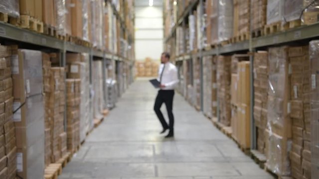 Gesch&auml;ftsmann kontrolliert Warenbestand im Lager einer Logistikfirma - Portrait erfolgreicher Businessmann // Businessman controls stock in the warehouse of a logistics company 