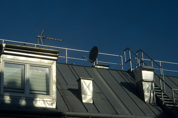 Sunny roof with attic, chimneys and TV antennas