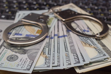 Handcuffs with money on the laptop keyboard. Top view