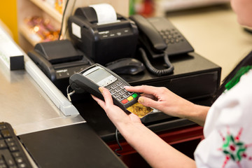 Woman hand with credit card swipe through terminal for sale, in market. Shopping and retail concept