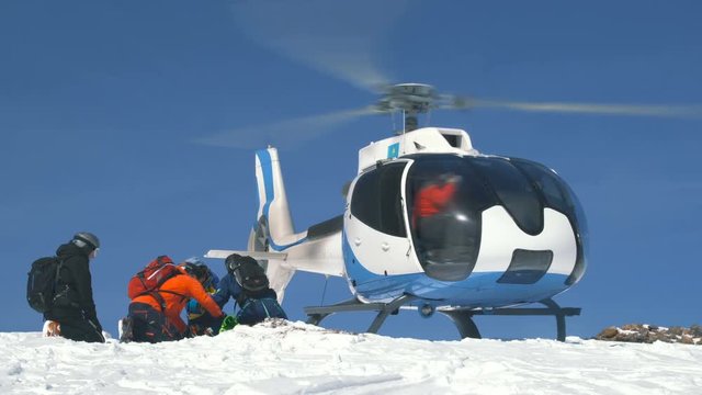Skiers sitting waiting for loading on the helicopter