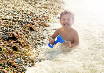 Nine month old baby boy sitting on the beach in beautiful summer day