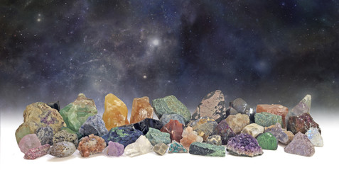 Cosmic Crystals Collection - dark deep space background with a neatly arranged collection of 40 different natural rough rock and gem specimens 
