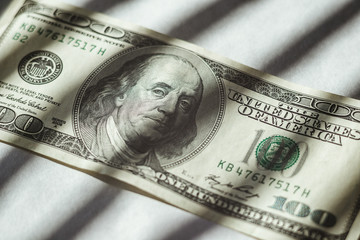 hundred-dollar bill of the USA with a shade from a lattice.