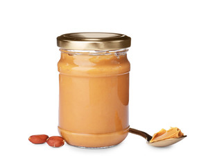 Jar and spoon with creamy peanut butter on white background