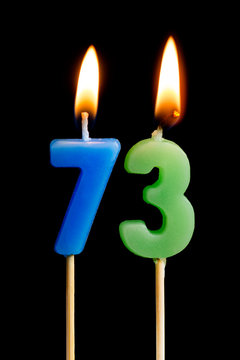 Burning candles in the form of 73 seventy three (numbers, dates) for cake isolated on black background. The concept of celebrating a birthday, anniversary, important date, holiday, table setting