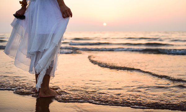 Girl walking on the beach wearing white dress