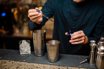 Barman adding blue dye into a shaker making summer cocktail