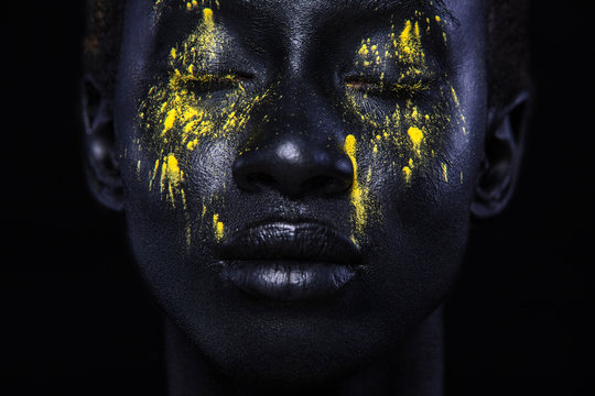 Cheerful young african woman with art fashion makeup. An amazing woman with black makeup and leaking yellow paint