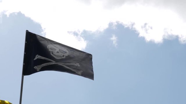 The pirate flag shake in the air in the blue sky background.